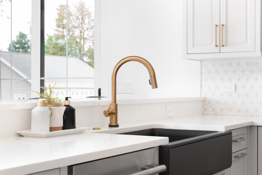 kitchen with white counters and black sink with gold faucet