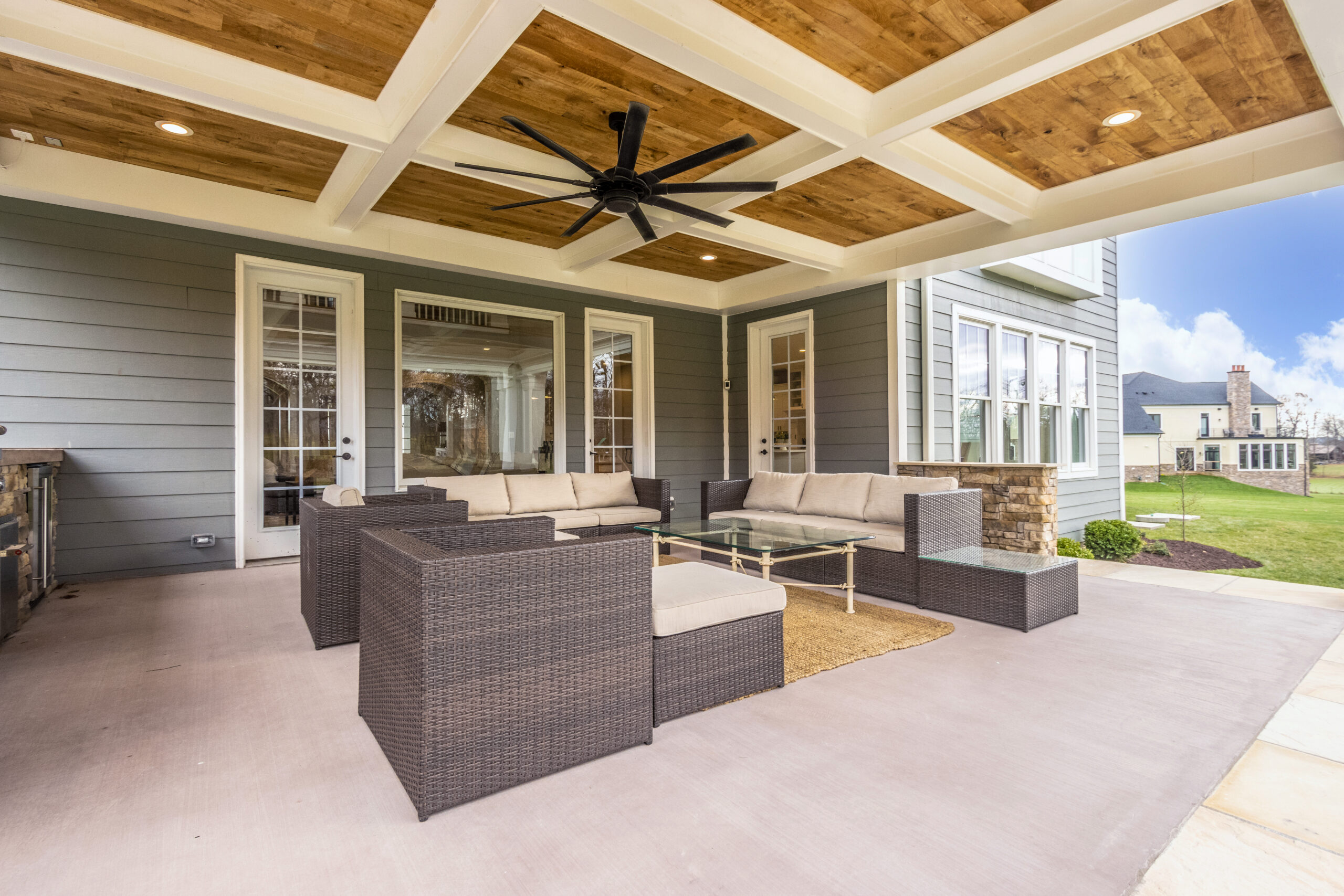 terrace with white and natural wood ceiling with a ceiling fan and grey-brown furniture