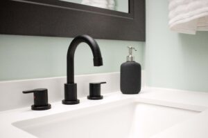 small bathroom with pale green walls with white sink and black faucet