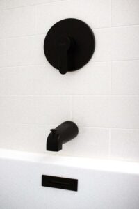 matte black faucet installed against white tiles