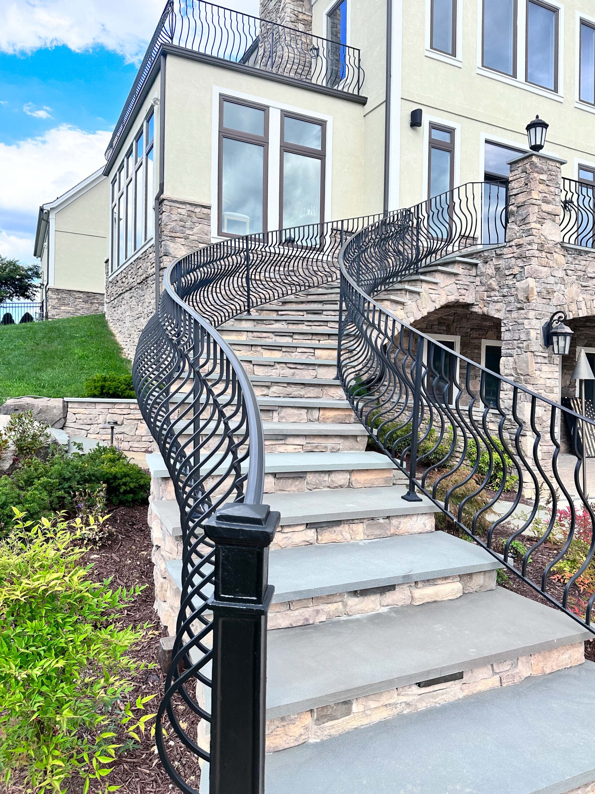 large stone staircase with iron railings leading up to a large yellow house