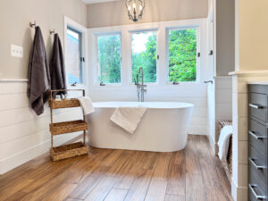 master bathroom with a large white tub under windows