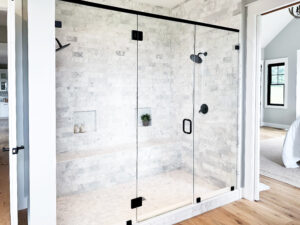 large glass shower with mottled white and black tiling