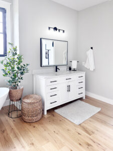 large master bathroom with white cabinets with white counters with a large mirror
